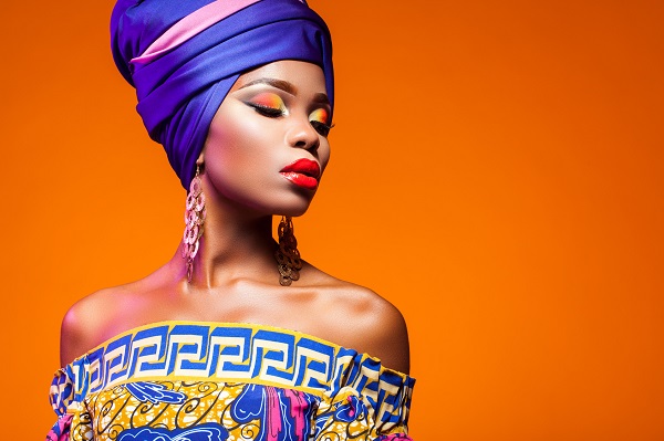 African woman in a bright dress on orange background
